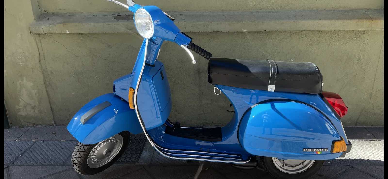 Blue Vespa PX 200 E photographed from the side